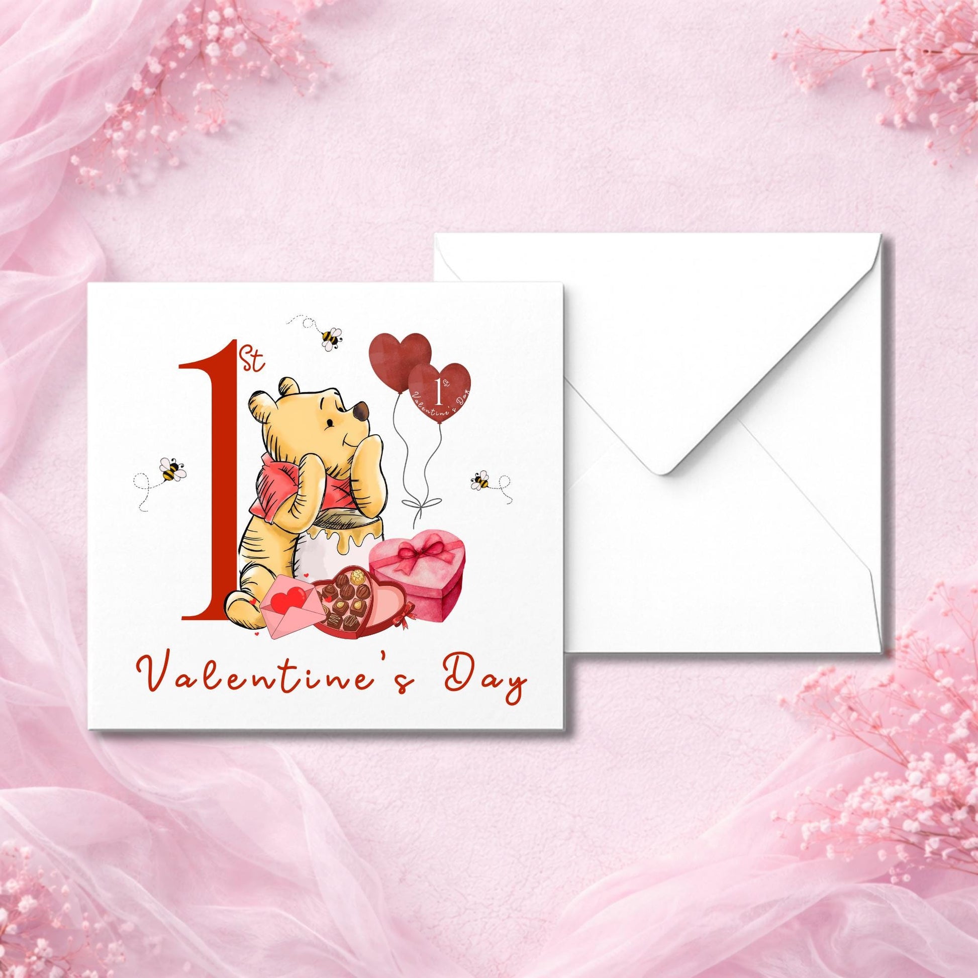 Valentine’s card for a baby featuring bear character holding heart and honey, surrounded by bees and gifts. Card says “1st Valentine’s Day” in red text. Perfect for gifting to new parents. Photographed flat lay with white envelope on soft pink fabric. Printed on thick smooth or hammered cardstock.