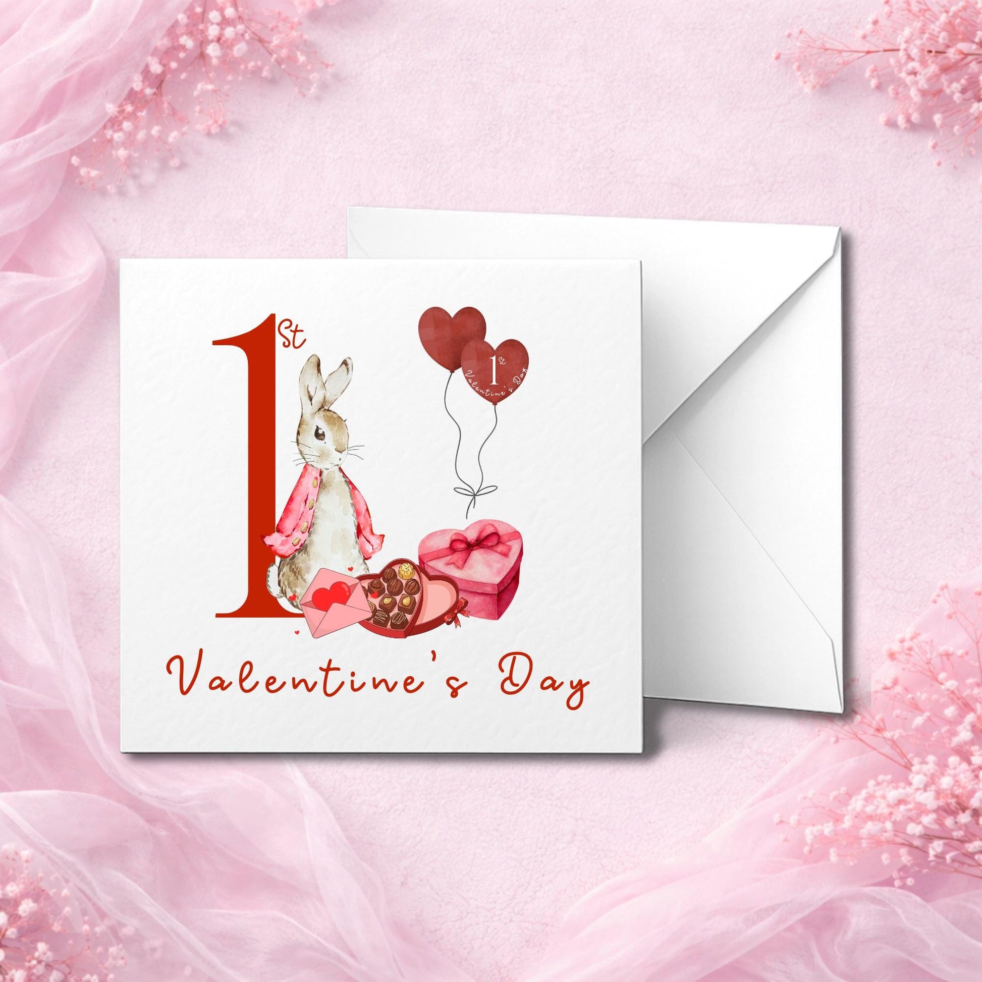 Handmade baby’s first Valentine’s Day card featuring a cute bunny in pink, sitting beside heart-shaped balloons and chocolates. The text “1st Valentine’s Day” is printed in red script. Photographed flat lay with white envelope on soft pink background. Available in smooth or hammered cardstock. Perfect keepsake card for baby girl, boy, or gender-neutral celebration.