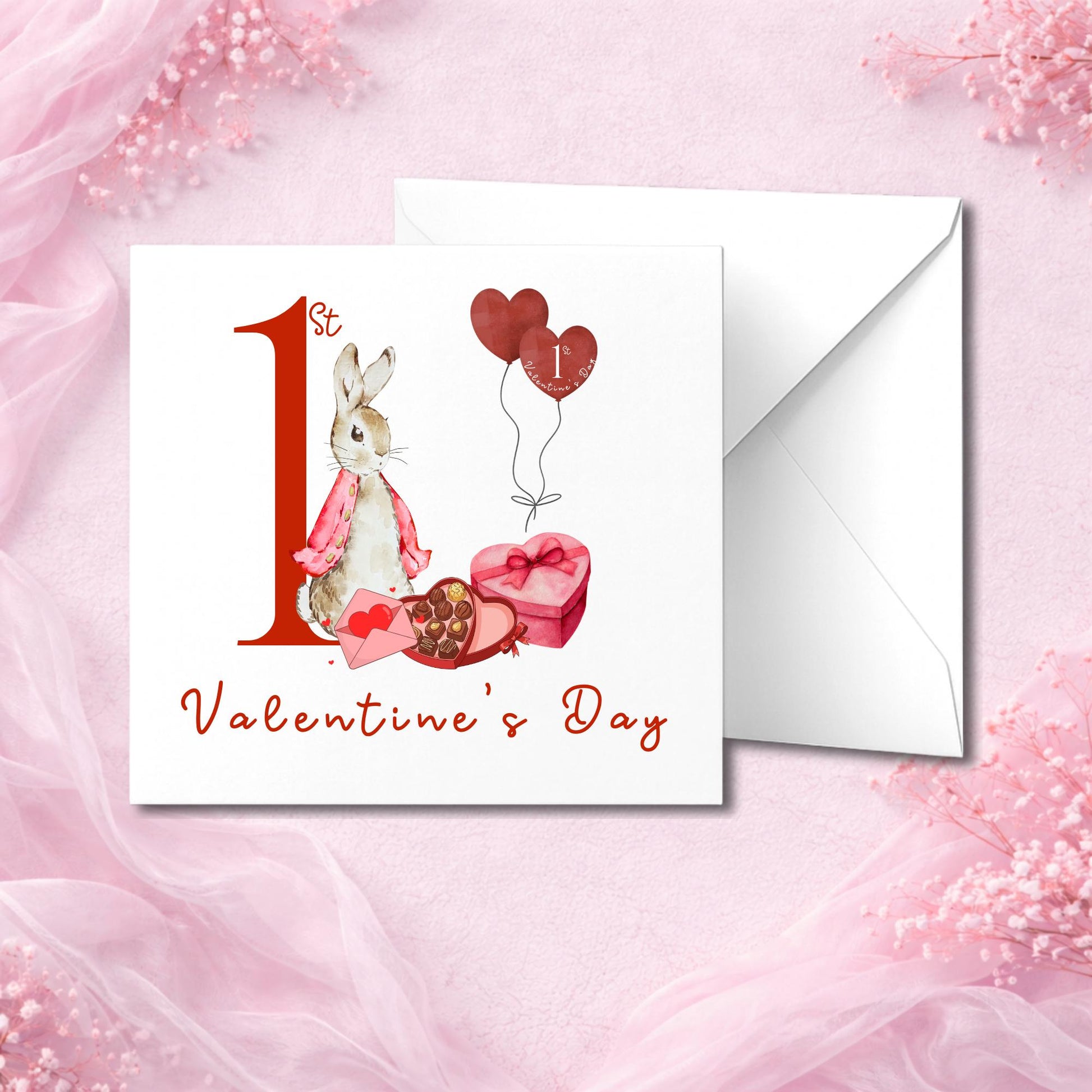 Flat lay greeting card design celebrating a baby's first Valentine’s Day. Bunny in soft neutral tones with heart-shaped chocolates and red balloons. Text reads “1st Valentine’s Day” in stylish red script. Printed on thick 300gsm card in hammered or smooth finish. Comes with crisp white envelope. Photographed against pink textured background with soft fabric.